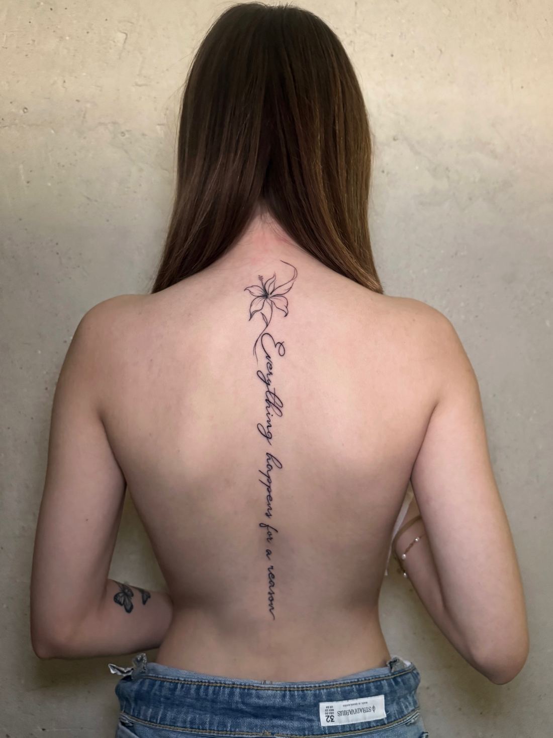 Tatuaje de fine line con una frase recorriendo la espalda